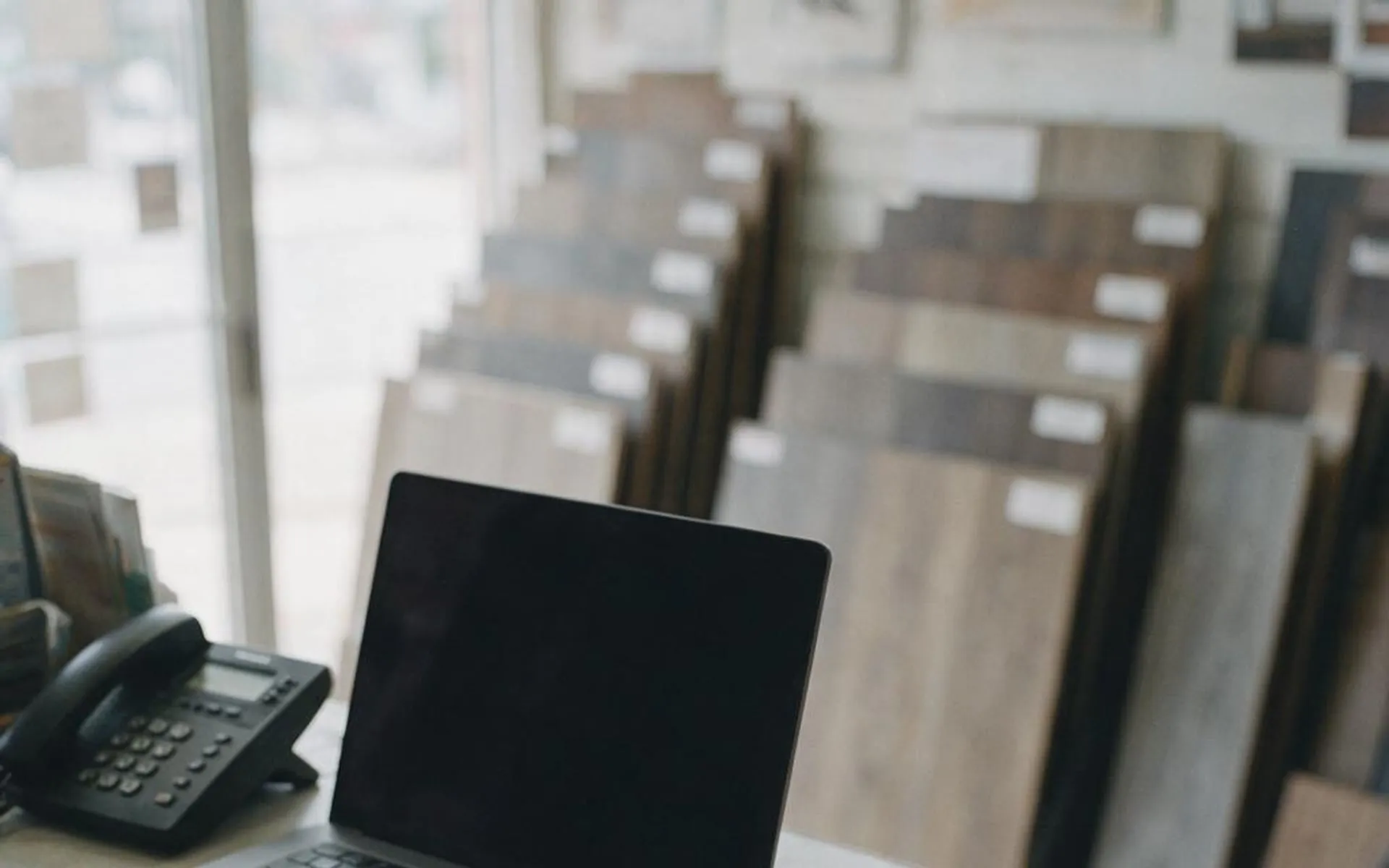 A flooring showroom counter with a laptop open beside the plank samples