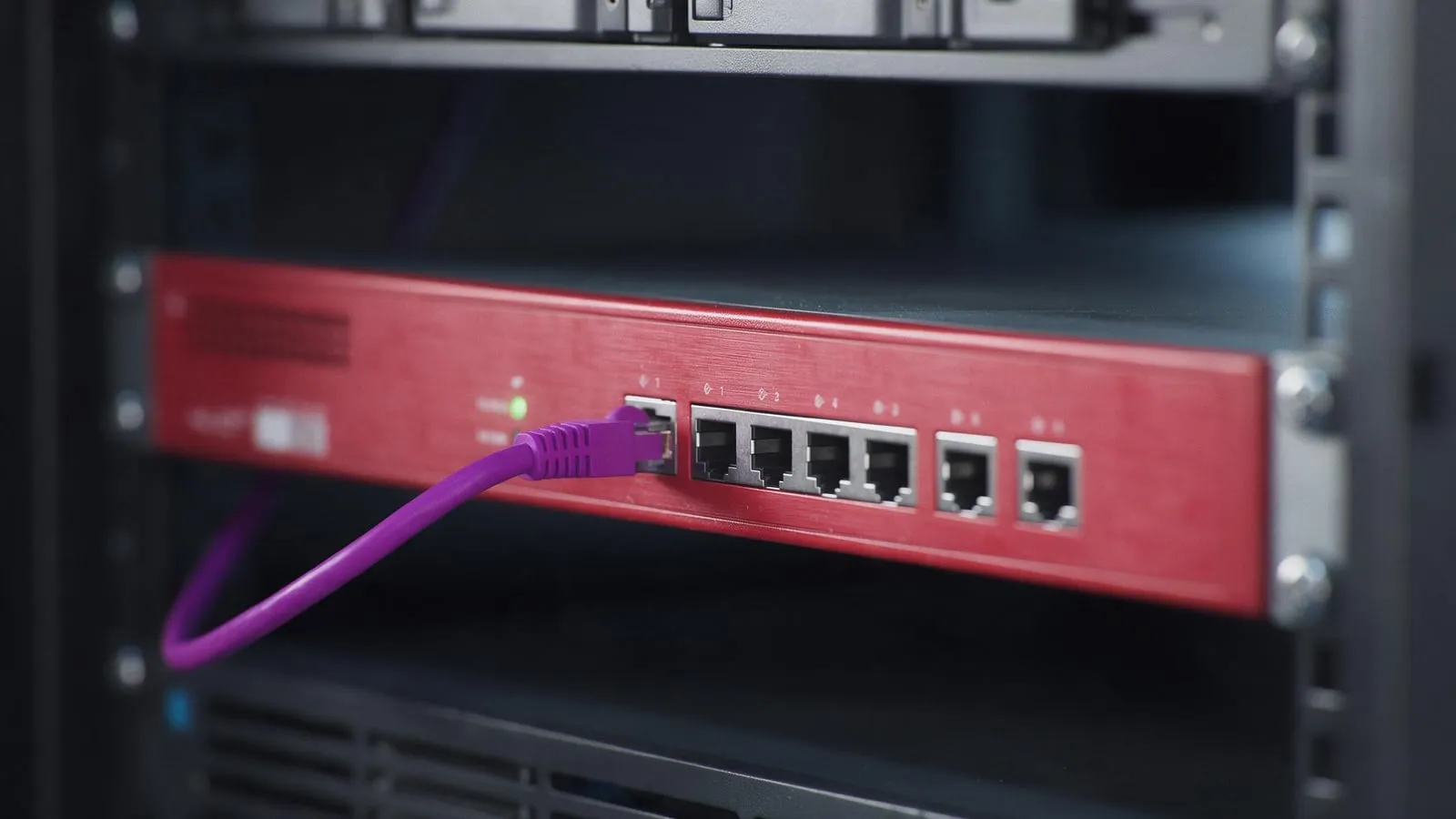 Macro of a red firewall appliance front panel with one green LED